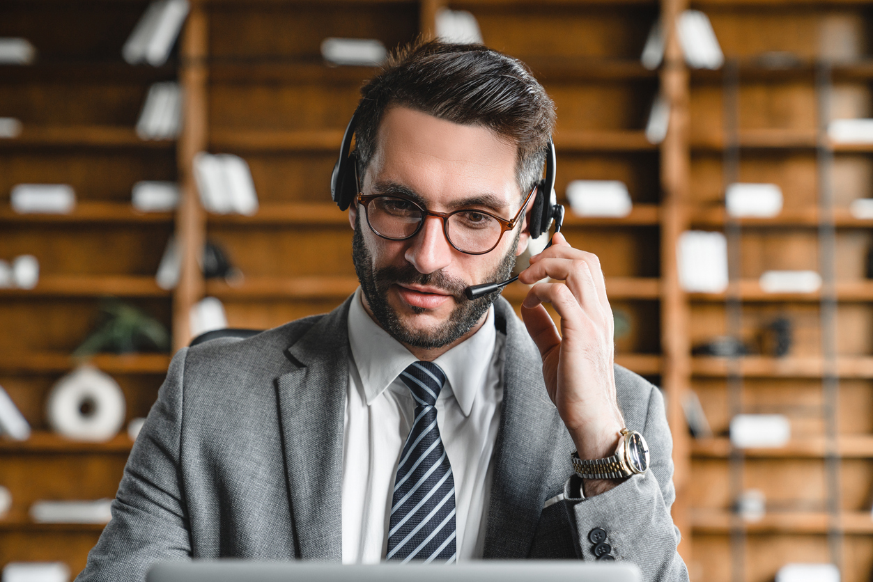 Confident Lawyer in headset consulting clients online in modern office